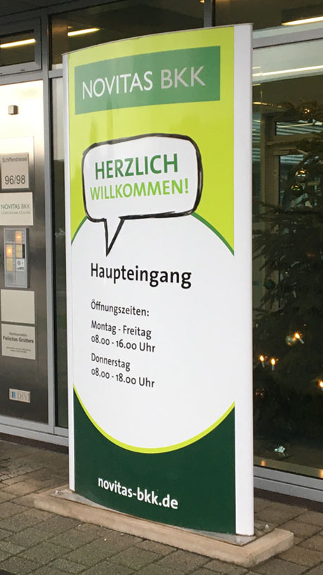 Stele als Informationsschild zur Orientierung vor einem Gebäude